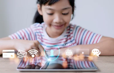 A young child uses a tablet with online safety icons surrounding it.