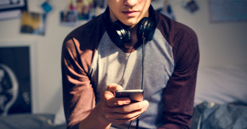 A teen looks at their phone, appearing worried.